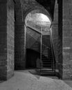 Black and white of dark abandoned underground passage with stone bricks columns and metal staircase Royalty Free Stock Photo