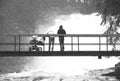 Black and white dashed retro sketch. erson with baby on bridge above troubled water. Huge stream below small footbridge. Fear of Royalty Free Stock Photo