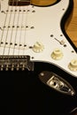 Black and white electric guitar details. Closeup: Body, bridge, single coil pickups, strings, jack, knobs, switch and pickguard.