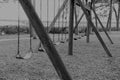 Black and white empty abandoned swings in a local park reflect our forgotten childhood