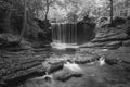 Black and white Epic beautiful Autumn landscape image of Nant Mill waterfall in Wales with glowing sunlight through the woodland Royalty Free Stock Photo