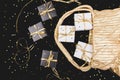 Black and white gift boxes with gold ribbon pop out from golden bag