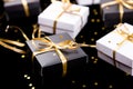 Black and white gift boxes with gold ribbon on shine background. Close up.