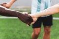 Black and white hands holding together in multiethnic group of young people playing football. team of people playing sport, symbol