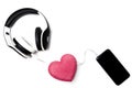 Black-white headphones with a smartphone on a white background, a symbol of love in the form of a heart in the middle of the wire Royalty Free Stock Photo