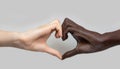 Black and white heart-shaped hands on a grey background. The concept of inter-racial friendship and respect