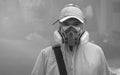 Asian healthcare worker in multi-purpose respirator half mask with protective clothing looking at camera in slum area