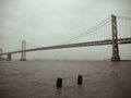 black and white image of the bay bridge on a rainy day from the embarcadero with boats