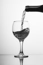 Black-white image of a bottle of wine and a glass. Pouring wine into a glass goblet on a high leg. Flowing liquid, wine drink, jet Royalty Free Stock Photo