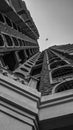 Black and white image of a building and airoplane in the sky.