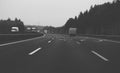Black and white image of cars trucks vans driving on highway tal