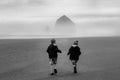Young boys run on empty beach backs to camera