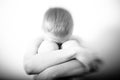 Black and white image of crying boy hugging knees