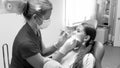 Black and white image of female pediatric dentist inspecting girls teeth