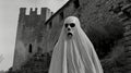 Black and white image of a ghostly figure in front of a medieval castle. Concept of ghost, haunted, horror, Halloween Royalty Free Stock Photo