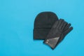 Black and white image of a knitted women`s hat and gloves on a blue background. Royalty Free Stock Photo