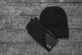 Black and white image of a knitted women`s hat and gloves on a wooden background. Royalty Free Stock Photo