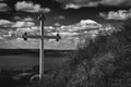 Black and white image of a large cross sitting on side of hill.