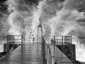 Black and white image of lighthouse in swell with splashing waves on Danish North Sea coast of VorupÃÂ¸r