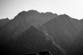 Black and white image of a mist covered mountain illuminated by sunlight with birds flying over. Winter concept Royalty Free Stock Photo