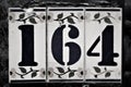 Black and white image. An old house number plate. Number 164. Royalty Free Stock Photo