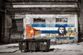 Black and white image of old shabby buildings in Havana with a painting of Che Guevara and a cuban flag