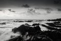 Black and white image of seashore and wave hitting rock on the b Royalty Free Stock Photo