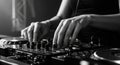 A black and white image shows hands of a person operating a DJ mixer. The