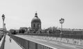 Black and white image of small child safely riding a bicycle alone on a scenic European bridge