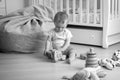 Black and white photo of toddler boy sitting on floor and playing with toy car Royalty Free Stock Photo