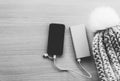 Mobile phone in winter charging from power bank, battery charger, on wooden background. Black and white image, top view. Royalty Free Stock Photo