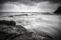 Black and white image wave flow on the sandy and rocky beach Royalty Free Stock Photo