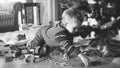 Black and white image of 4 years old little boy playing with toy railroad and train on floor at living room under Royalty Free Stock Photo