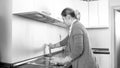 Black and white image of young housewife washing kitchen with detergent spray Royalty Free Stock Photo