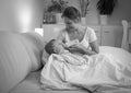 Black and white photo of young mother feeding her baby son with milk from bottle at night Royalty Free Stock Photo