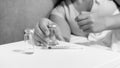 Black and white image of young woman lying in bed taking ampules with medicines and syringe from bedside table