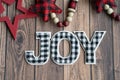 Black and white joy plaid phrase on a wood background with red stars, useful for Christmas projects Royalty Free Stock Photo