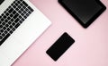 Black-white laptop keyboard, black tablet, black mobile phone on a pink background. Copy space. Top view. Computer work. Flat lay