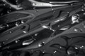 Black and white macro photo of water drops scattered on reflective metal surface