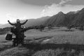 Black and white. Man motorcyclist happy destination scene. Motorcycle adventure. Alpine mountains on background. Biker lifestyle,