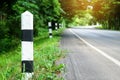 Black and white milestones with green grass roadside, Trees road