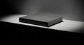 A black and white minimalistic photograph of a rectangular glossy box on a white surface with a low angle view and dramatic shadow Royalty Free Stock Photo
