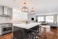 A black and white modern kitchen looking towards a living room.