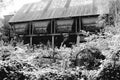 Black and white monochrome image of an old abandoned overgrown industrial unit with numbered steel hoppers