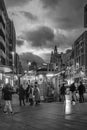 Black and white night view of people passing near a street kiosk in Callao Madrid Spain