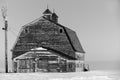 Black and white of an old, abandoned prairie barn surrounded by snow in Saskatchewan