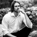 Black-white outdoor portrait of elegant long hair handsome man siting near pond Royalty Free Stock Photo