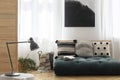 Black and white painting above scandinavian futon with pillows in trendy living room interior, real photo with mockup on the empty