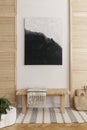 Black and white painting above wooden bench with striped blanket in natural waiting room, real photo with mockup on the empty wall