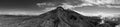 Black and white panarama of the vulcano Chimborazo that has a white top covered in snow and shows five of the mountain ridges